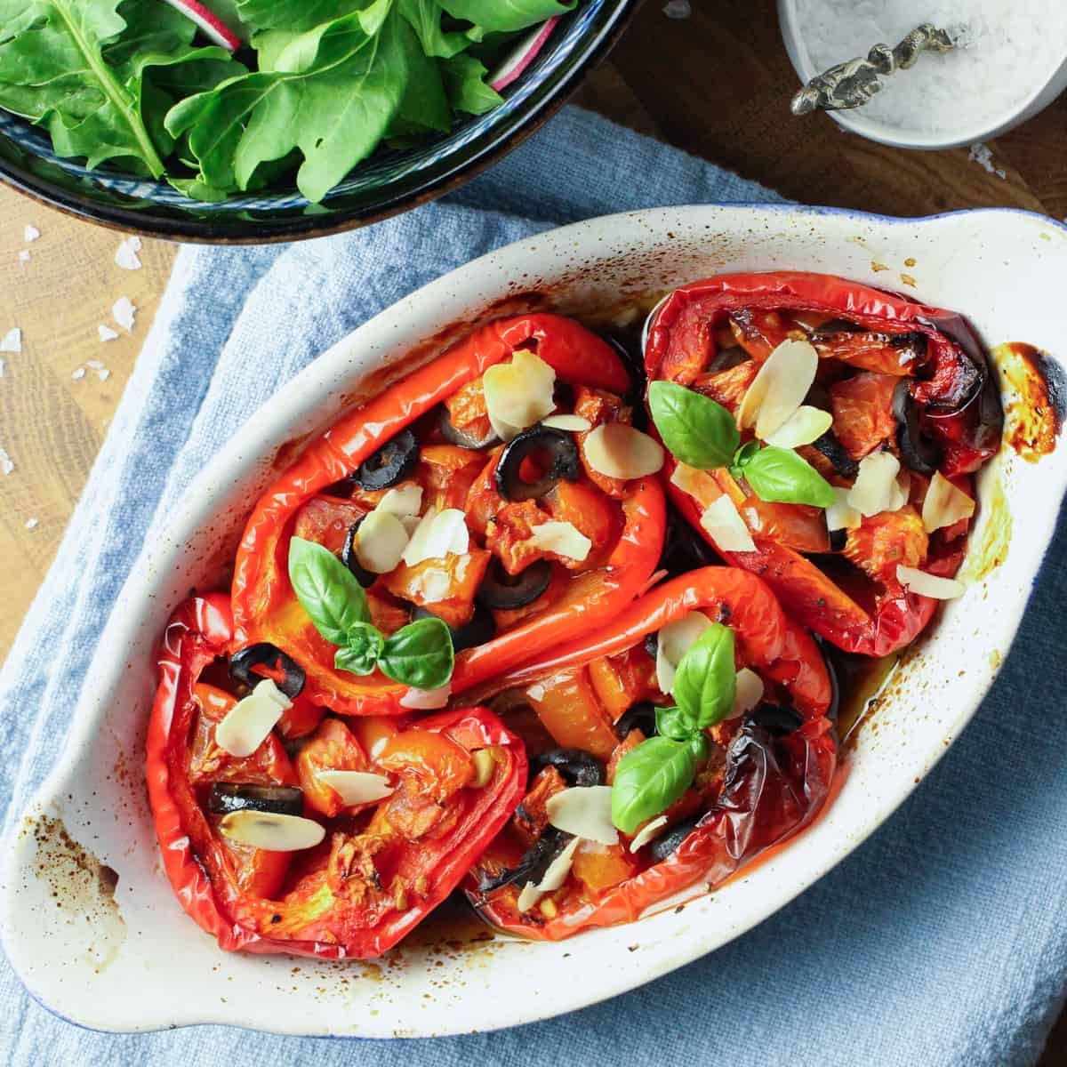 Photo of roasted red peppers in a roasting dish with basil garnish